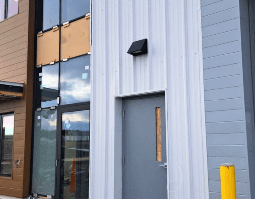 Metal sliding Commercial building exterior with white corrugated metal siding and gray steel door