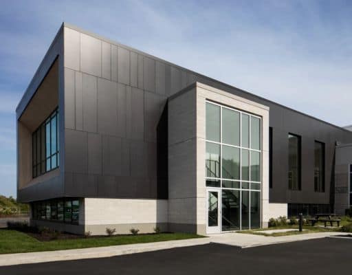 cement Modern commercial building exterior with dark metal cladding and large glass entrance